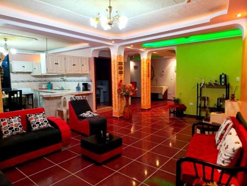 - un salon avec des chaises rouges et un mur vert dans l'établissement Amplio y cómodo departamento con garage, à Puyo