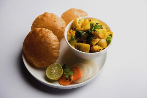 a plate of food with a bowl of soup and bread at Flagship 81024 Fabulous Home Stay in New Delhi