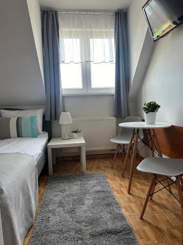 a small bedroom with a bed and a table at Pensjonat Melodia in Pobierowo