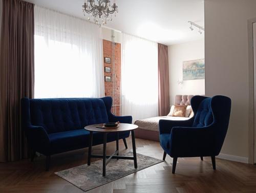 a living room with two blue chairs and a table at Old street apartment in Šiauliai