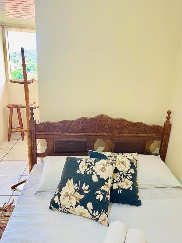 a bed with a wooden headboard and two pillows on it at Hospedaria Vila Rica - 1 km do centro histórico in Ouro Preto