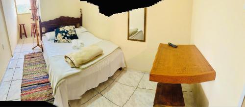a bedroom with a bed and a wooden table at Hospedaria Vila Rica - 1 km do centro histórico in Ouro Preto