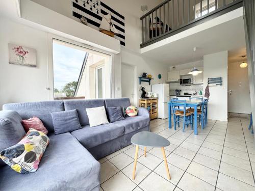 ein Wohnzimmer mit einem blauen Sofa und einer Küche in der Unterkunft Charmant T3 duplex 2 Bord de mer Terrasse in Quiberon