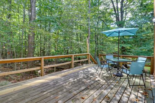 a wooden deck with a table and an umbrella at Poconos Cabin Serene Deck, Fire Pit and Game Room in Tobyhanna