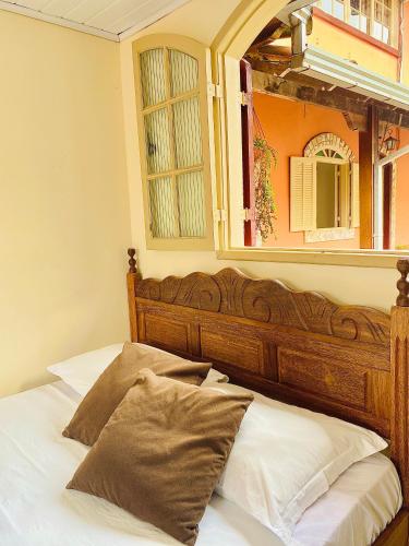 a bed with a wooden headboard and a mirror at Hospedaria Vila Rica - 1 km do centro histórico in Ouro Preto