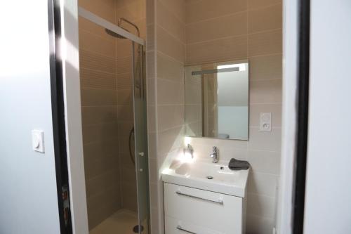 a bathroom with a sink and a shower with a mirror at Duplex climatisé in Aramits