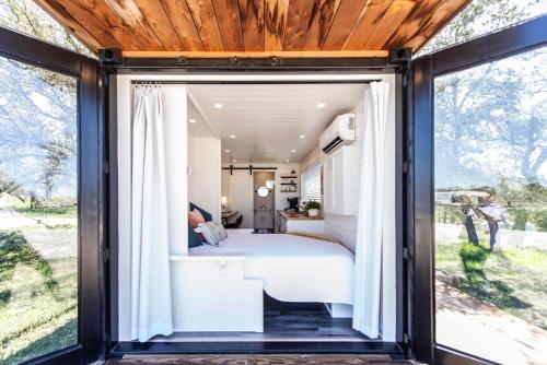 a bedroom in a tiny house with sliding glass doors at New Oak Grove-Container Retreat in Fredericksburg