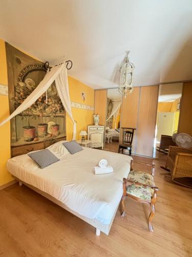 ein Schlafzimmer mit einem großen weißen Bett und einem Stuhl in der Unterkunft La Villa de la Chapinière in Châteauvieux
