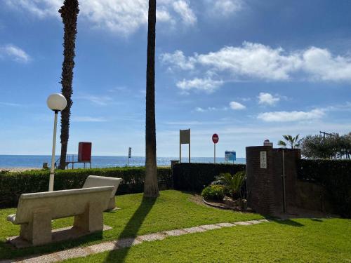 a bench sitting in the grass near the beach at Playa Esquirol in Cambrils