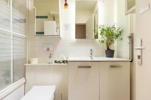 a bathroom with white cabinets and a sink and a potted plant at Chbre 2P + navette CDG in Aulnay-sous-Bois