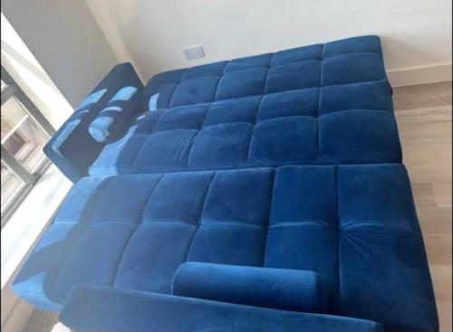 a blue bed in a room with blue sheets at Modern Stylish Apartment in Birmingham in West Bromwich