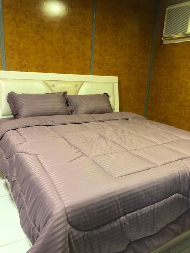 a large bed with purple sheets and pillows at شاليه نزل أمنة in Sīdī Ḩamzah