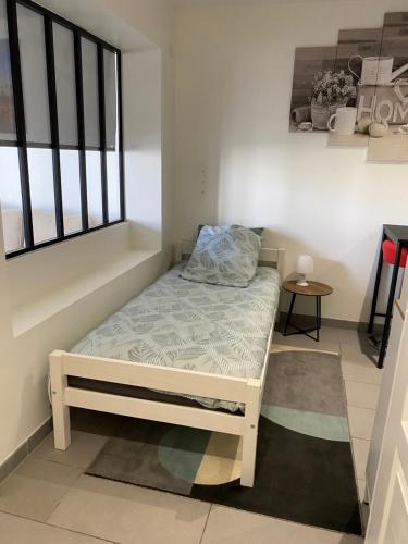 un petit lit dans une chambre avec une fenêtre dans l'établissement Jolie perle, à Saint-Priest