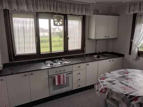 cocina con armarios blancos, fregadero y mesa en Villa en la costa, en Santander