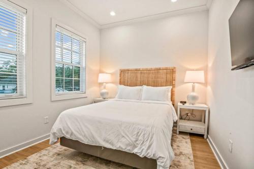 a white bedroom with a large bed and two windows at Ship Island Town Home in Pass Christian