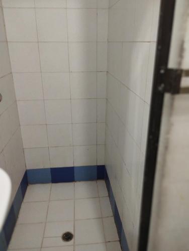 baño con ducha con azulejos blancos y desagüe en Apartamentos Ganen en Cartagena de Indias