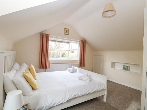 a white bed in a room with a window at Swan Dyke Cottage in Horning