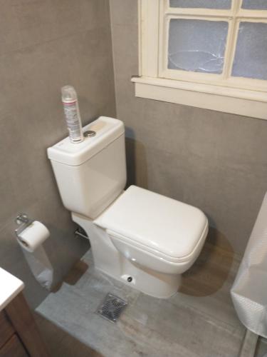 La salle de bains est pourvue de toilettes blanches et d'une fenêtre. dans l'établissement PLAZA SAN MARTIN, à Buenos Aires