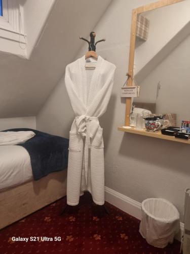 a white robe hanging on a wall next to a bed at St Leonards Guest House in Largs