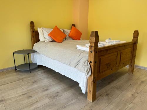 ein Schlafzimmer mit einem Holzbett mit orangefarbenen Kissen in der Unterkunft Apartment Happy Place 2 in Weliko Tarnowo