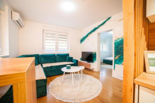 a living room with a green couch and a table at Apartment Vila Idila in Tuzla