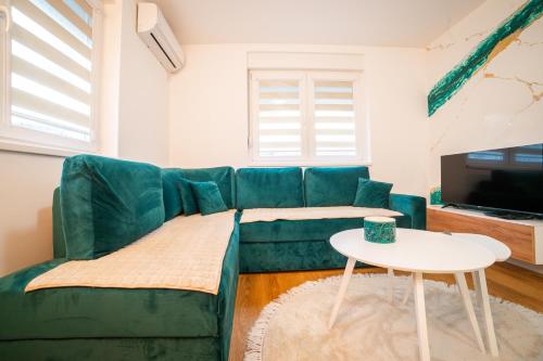 a living room with a green couch and a table at Apartment Vila Idila in Tuzla