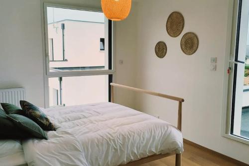 un lit blanc dans une chambre avec une fenêtre dans l'établissement Maison moderne et lumineuse à 5 minutes à pied des plages, à Landunvez