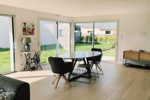 d'une salle à manger avec une table et des chaises dans le salon. dans l'établissement Maison moderne et lumineuse à 5 minutes à pied des plages, à Landunvez