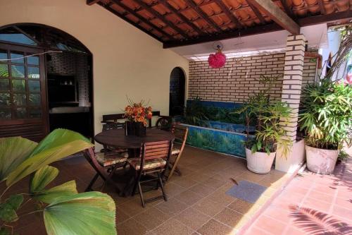 a patio with a table and chairs and plants at Nana's House Vilas in Lauro de Freitas