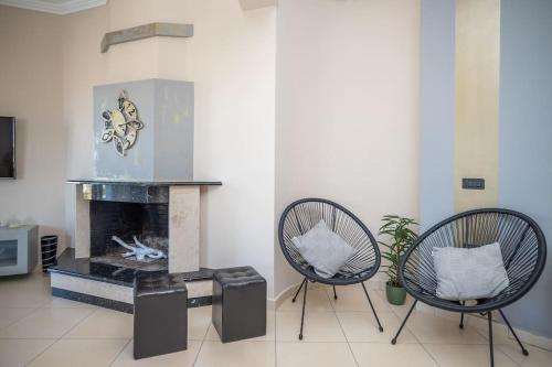 a living room with two chairs and a fireplace at La Vie Villa in Zakynthos Town