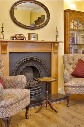 a living room with a fireplace with two chairs and a table at Windsor/Legoland/Ascot charming 3BR home in centre in Windsor