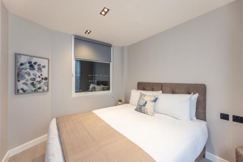 a bedroom with a white bed with a window at Diff-Rent Living in Harrow