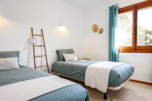 um quarto com duas camas e uma escada e uma janela em Casa Bernia Vista em Benitachell