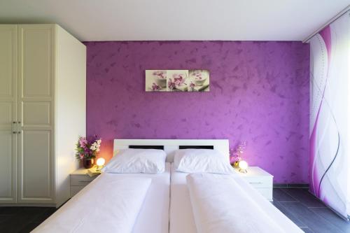 1 Schlafzimmer mit 2 Betten und einer lila Wand in der Unterkunft Sunnewies in Wildhaus