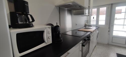 Il comprend une cuisine équipée d'un four micro-ondes et d'un comptoir noir. dans l'établissement Berthe Lydie Cottage Charme, Confort et Mer, à Fort-Mahon-Plage