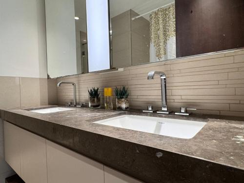 uma casa de banho com 2 lavatórios e um espelho grande em CityVibesDxb em Dubai