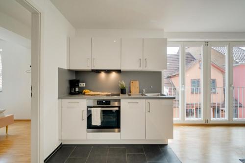 a kitchen with white cabinets and a large window at Altstadt Apartment 2 Zimmer am Weibermarkt in Reutlingen