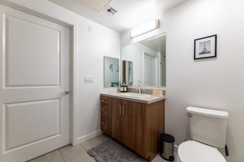 a bathroom with a toilet and a sink and a mirror at Luxury Home in Hollywood with Pool I Gym I Free Parking in Los Angeles