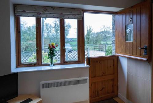 Habitación con ventana y jarrón de flores en The Burcott Inn Cottages, en Wells