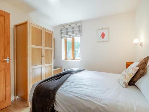 a bedroom with a white bed and a wooden cabinet at The Burcott Inn Cottages in Wells
