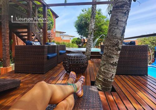 a woman is laying on a wooden deck with her feet at Calador Búzios Hotel in Búzios