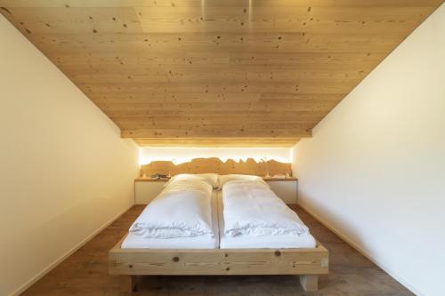a bed in a room with a wooden ceiling at Schönau in Wildhaus