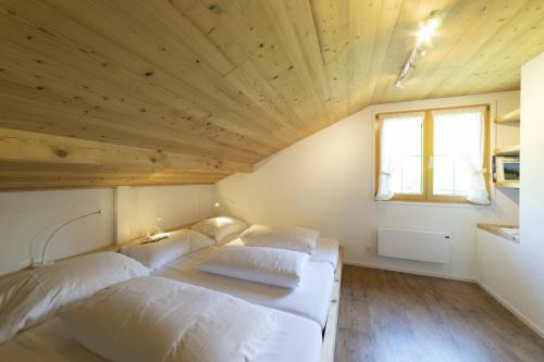 two beds in a room with a wooden ceiling at Schönau in Wildhaus