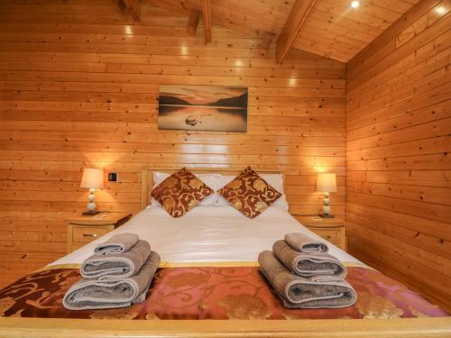 een bed in een houten kamer met handdoeken erop bij Chywolow Lodge in Morvah