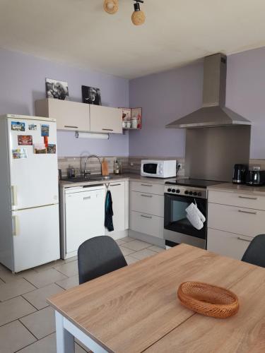 Appartement RDC avec terrasse في Épinac-les-Mines: مطبخ بأدوات بيضاء وطاولة خشبية