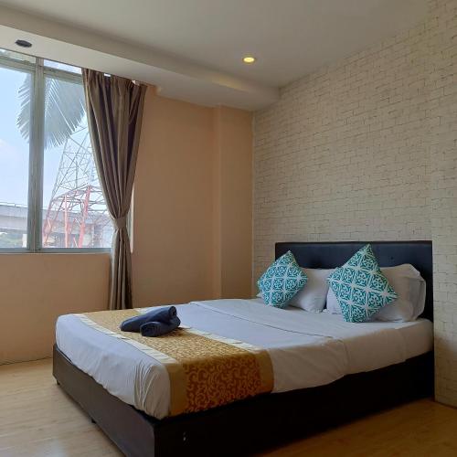 a bedroom with a bed with blue pillows and a window at The Patioz Boutique Hotel in Kajang