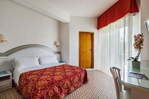 チェゼナーティコにあるHotel Caravelleのベッドルーム1室(ベッド1台、テーブル、窓付)