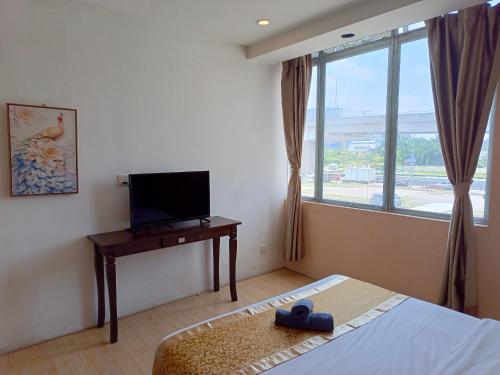 um quarto com uma cama, uma televisão e uma janela em The Patioz Boutique Hotel em Kajang