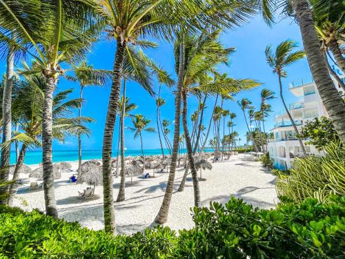 a beach with palm trees and the ocean at DUCASSI SUITE Sol Karibe SUITES STUDIOS TROPICANA Rooftop POOL WiFi Beach & SPA in Punta Cana