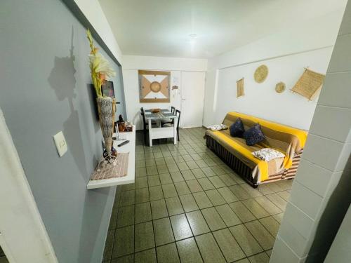 uma sala de estar com um sofá amarelo e uma mesa em Confortável quarto e sala com Manobrista, Wi-fi, Tv Smart - Apto 208 em Maceió